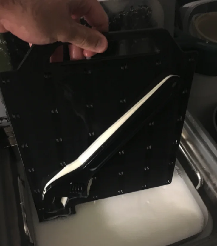 Placing the 3D print into a soluble water bath. - Fictiv Placing the 3D print into a soluble water bath.