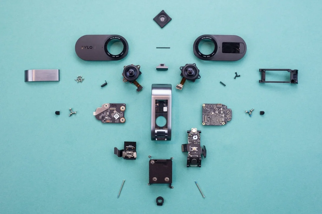 Rylo-Teardown_hero - Fictiv image of two small cameras taken apart and arranged symmetrically on a light blue background