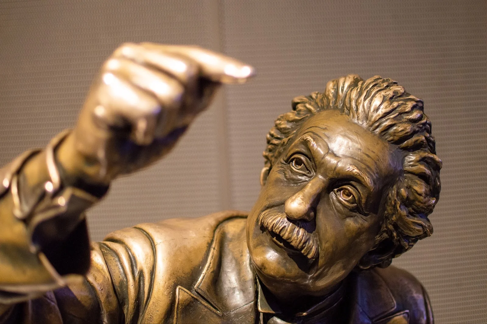 bronze state of albert Einstein looking up with his hand raised