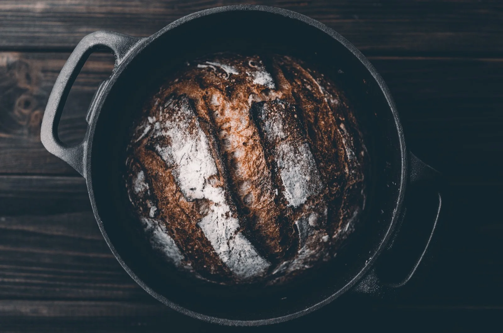 cast iron pot with a loaf of baked bread
