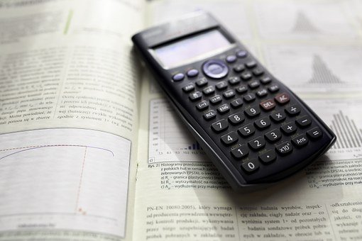 a scientific calculator sitting on top of an open statistics textbook