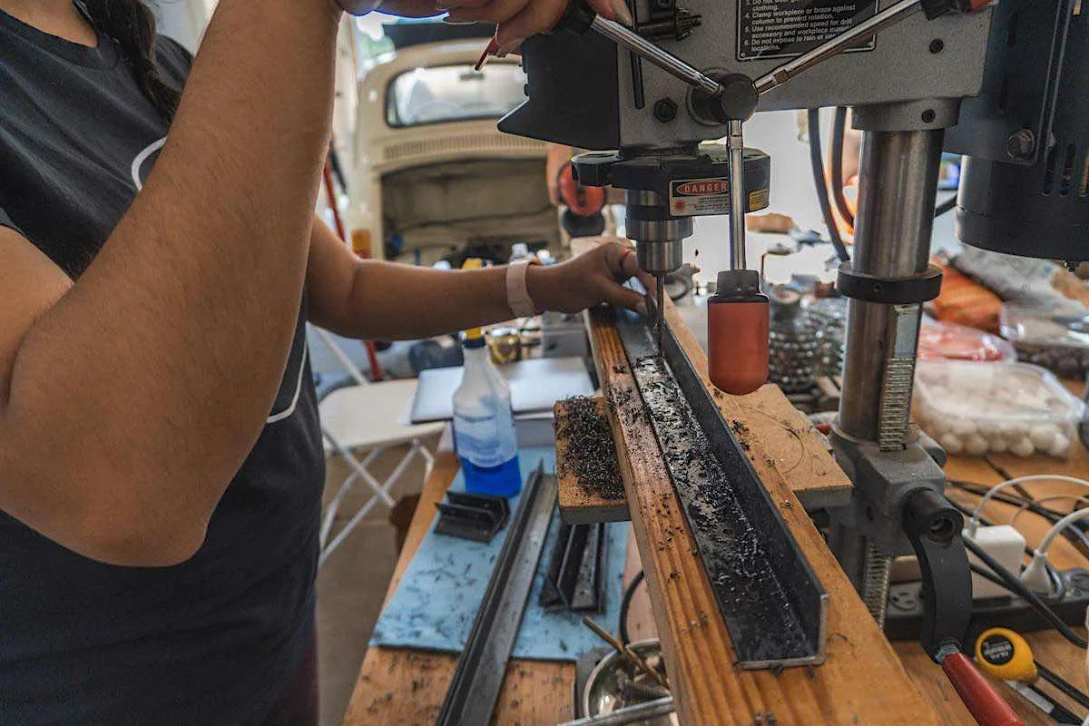 image of a person drilling holes in a steel angle bar using a drill press