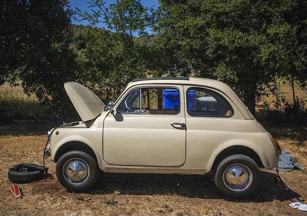image of a tan 1966 fiat 500 on jack stands with the front trunk open