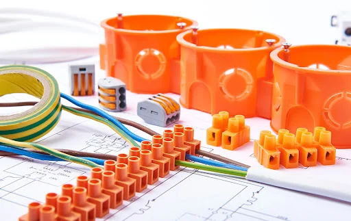 Electrical connectors with wires, junction box and different materials used for jobs in electricity. Many tools lying on diagrams. Concept of electrical works.
