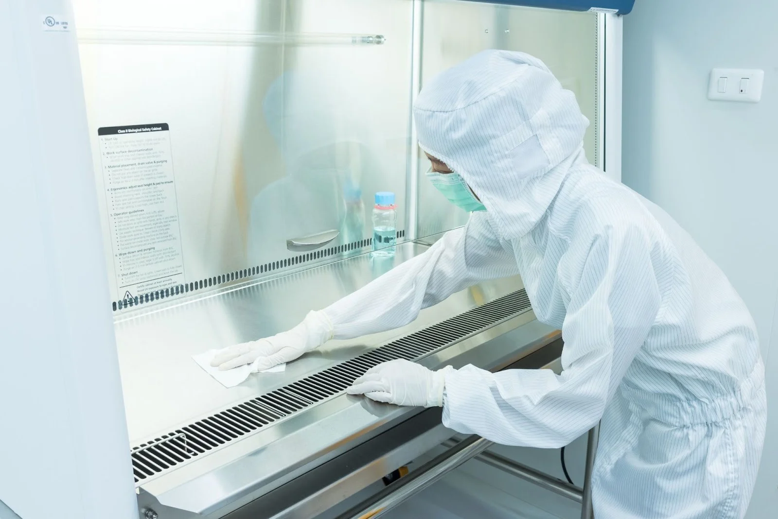 A manufacturing worker cleaning a biological safety cabinet used for assembly.