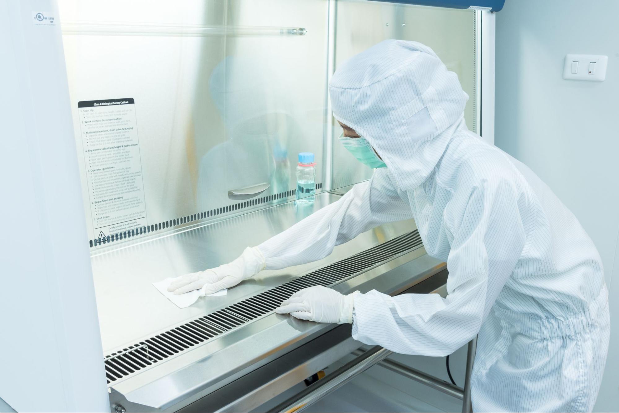 A manufacturing working cleaning a biological safety cabinet used for assembly.