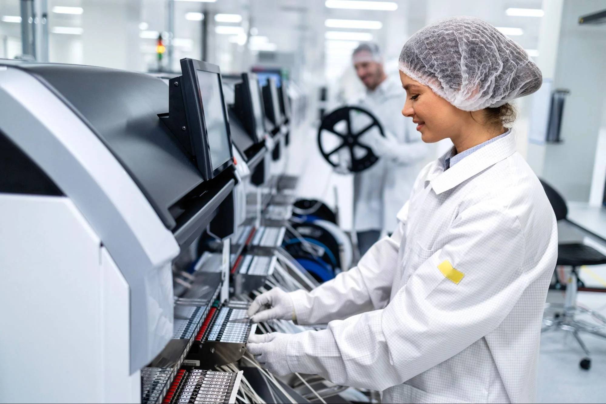  Factory worker operating a semiconductor production machine in the electronics industry.
