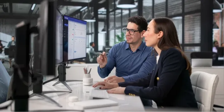 
																Two colleagues reviewing compliance details at a desk