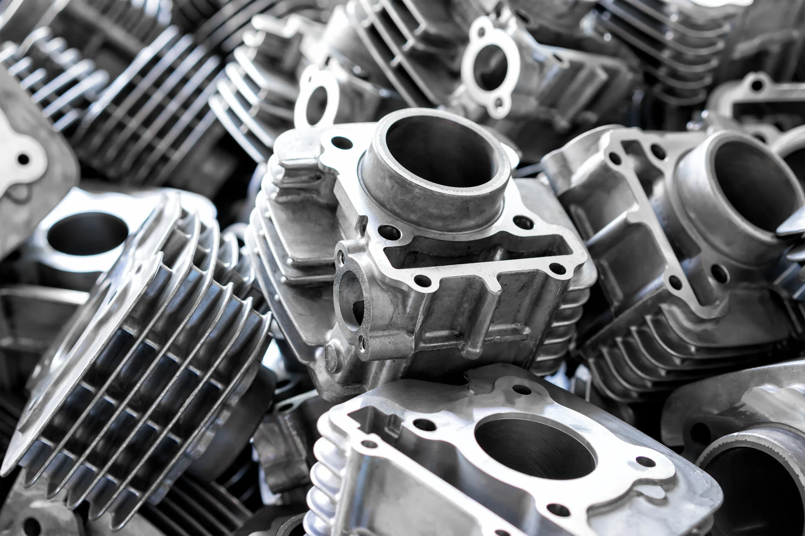 Pile of aluminum automotive parts body cylinder casting process in the industry factory - Fictiv Gray aluminum die-cast engine blocks and cylinders stacked together