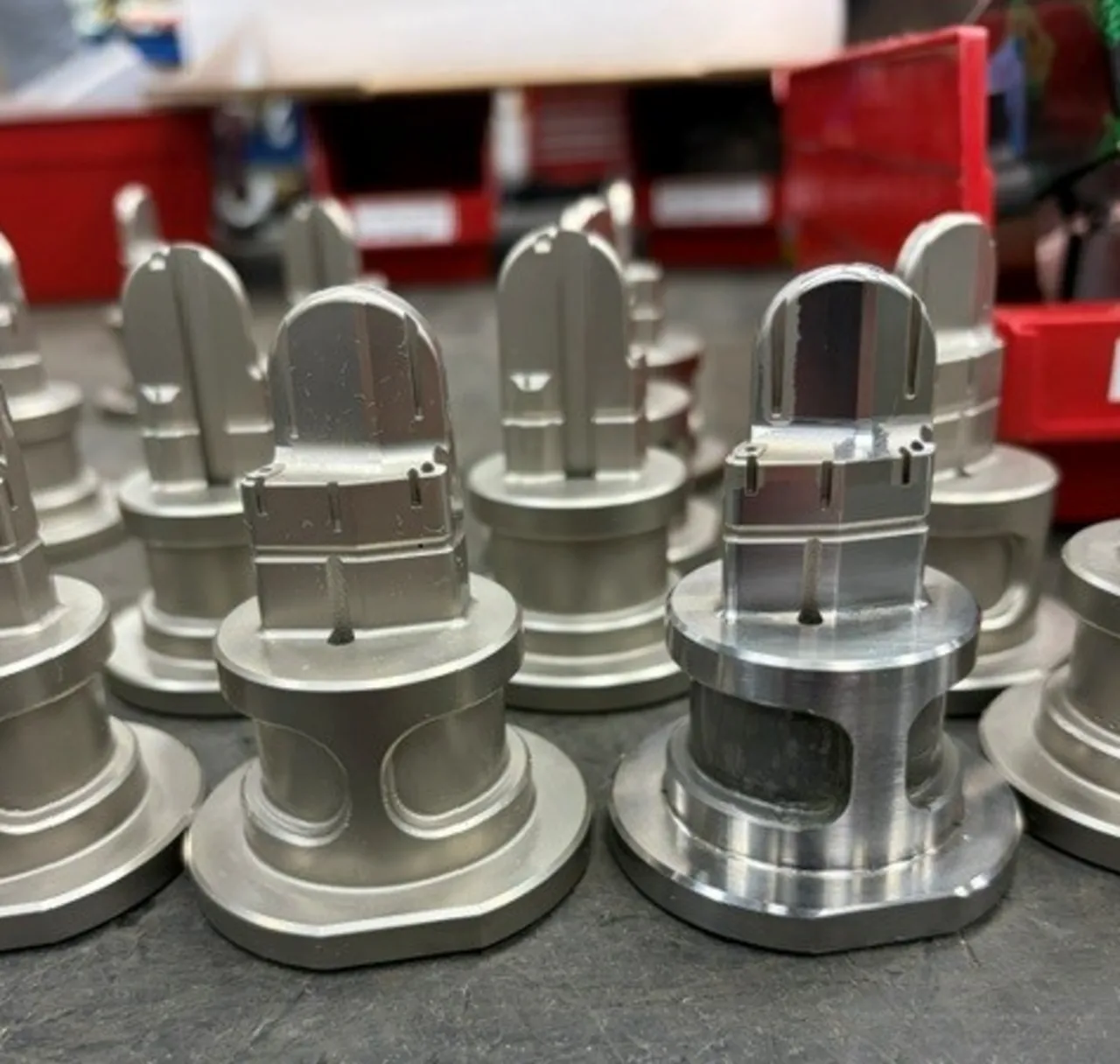 Row of stainless steel valve-like components on a workbench in a workshop.