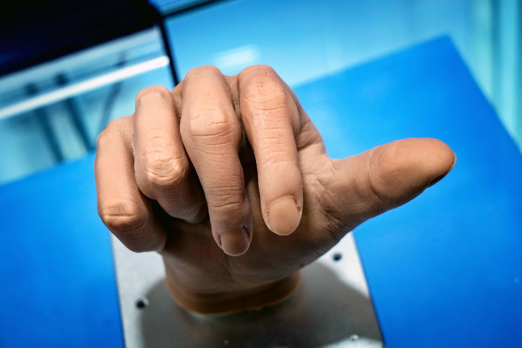 Close-up of a hand with fingers pressed together against a blue background surface