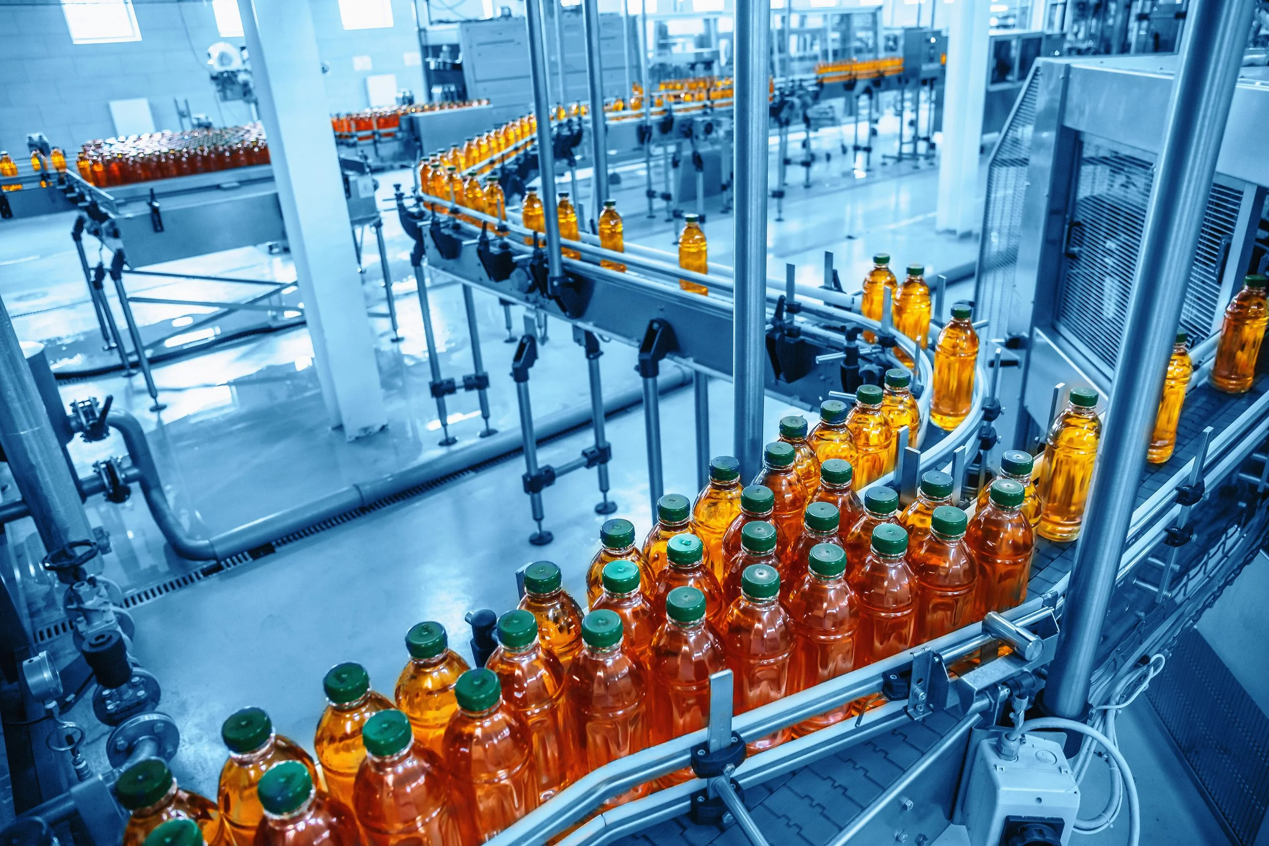 Conveyor belt juice in bottles on beverage plant or factory interior in blue color industrial production line - Fictiv Beverage bottling assembly line